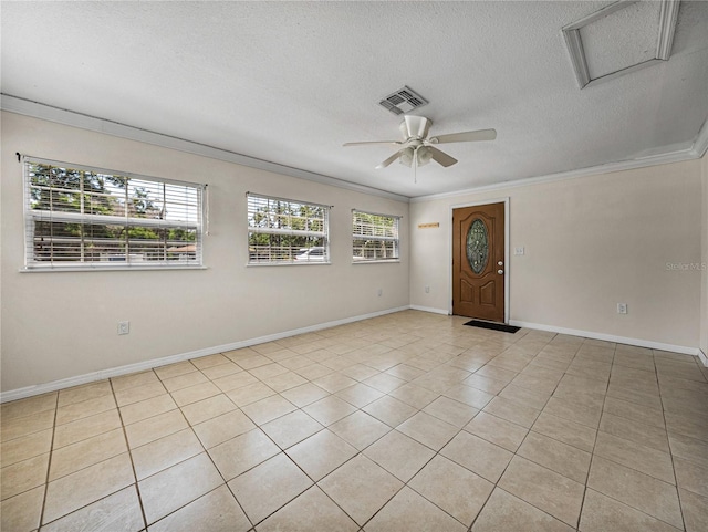 tiled empty room featuring visible vents, baseboards, ceiling fan, a textured ceiling, and crown molding