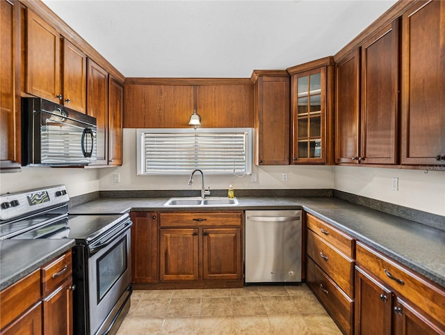 kitchen with a sink, glass insert cabinets, appliances with stainless steel finishes, and dark countertops