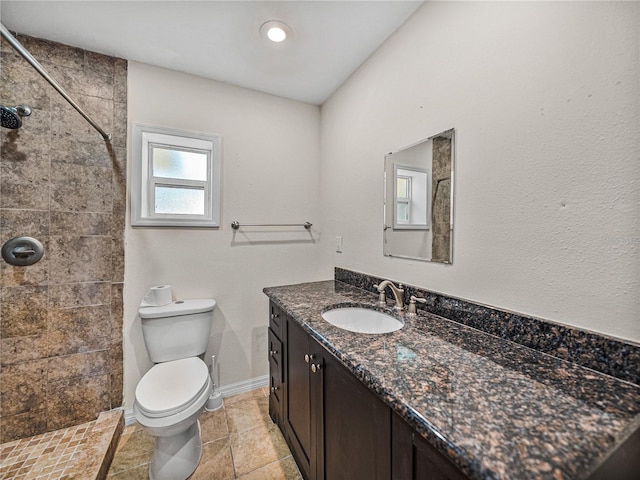 bathroom featuring vanity, baseboards, tile patterned flooring, toilet, and tiled shower