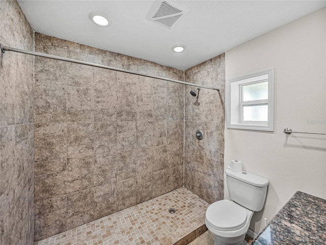 full bath featuring toilet, tiled shower, and visible vents