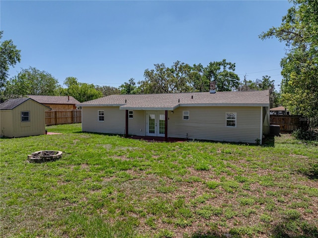 back of property featuring an outdoor fire pit, french doors, fence, and a lawn
