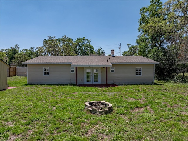 rear view of property featuring a yard, a fire pit, fence, french doors, and a chimney