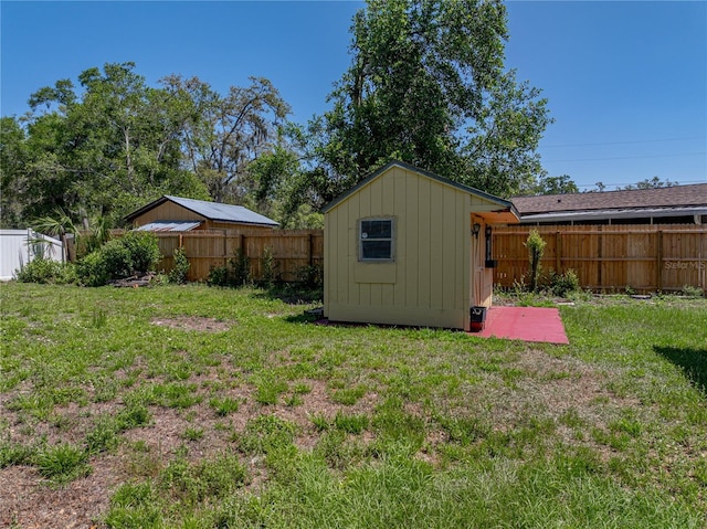 view of yard with a fenced backyard, an outdoor structure, and a storage unit