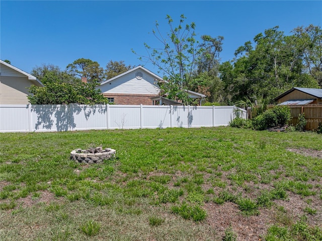 view of yard featuring a fenced backyard and a fire pit