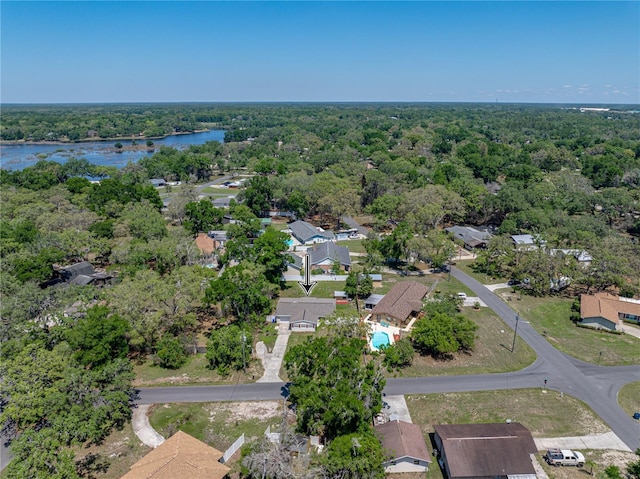 drone / aerial view with a wooded view, a residential view, and a water view