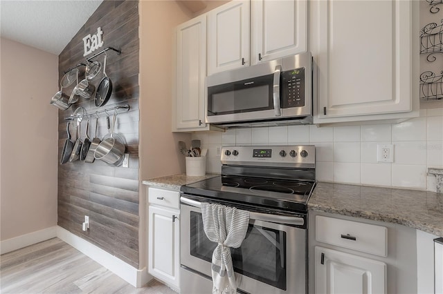 kitchen featuring decorative backsplash, appliances with stainless steel finishes, white cabinets, and baseboards