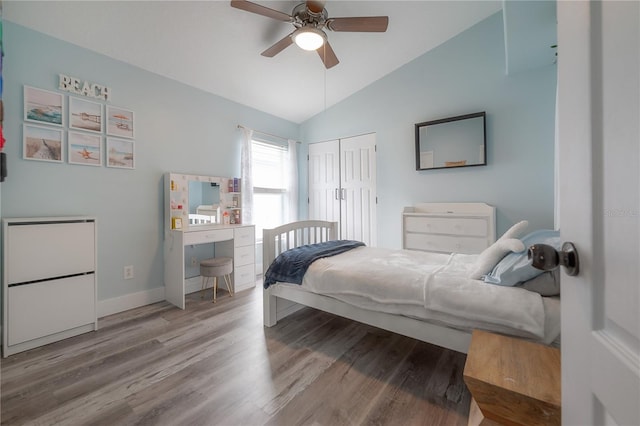 bedroom featuring a closet, wood finished floors, baseboards, ceiling fan, and vaulted ceiling