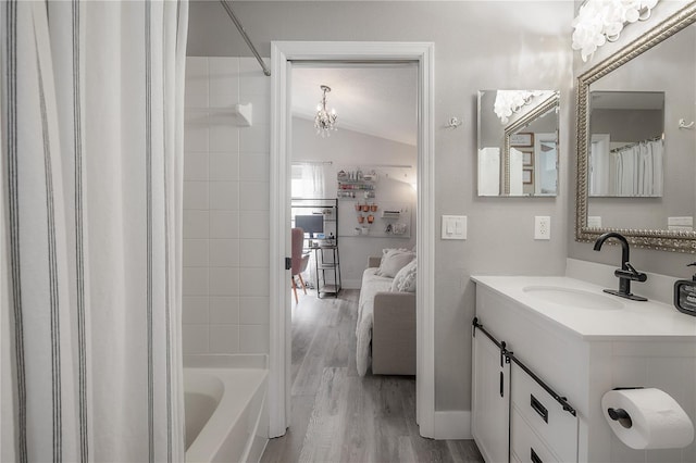 full bath with an inviting chandelier, ensuite bath, vanity, wood finished floors, and lofted ceiling