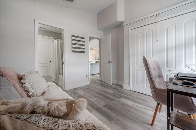 home office featuring arched walkways, baseboards, visible vents, and light wood finished floors