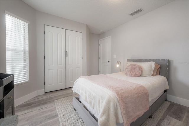 bedroom featuring visible vents, baseboards, and light wood finished floors