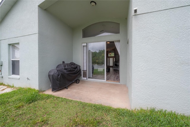 view of exterior entry with a patio and stucco siding