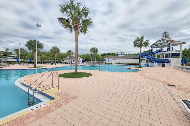 pool with fence, a water slide, a gazebo, and a patio area