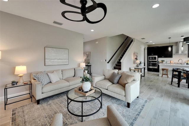 living area with visible vents, ceiling fan, light wood finished floors, recessed lighting, and stairs