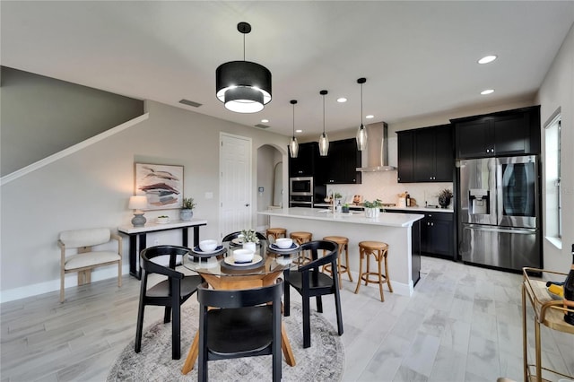 dining space featuring arched walkways, visible vents, recessed lighting, light wood finished floors, and baseboards
