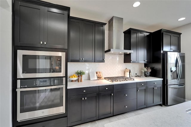 kitchen with light countertops, wall chimney exhaust hood, decorative backsplash, and stainless steel appliances