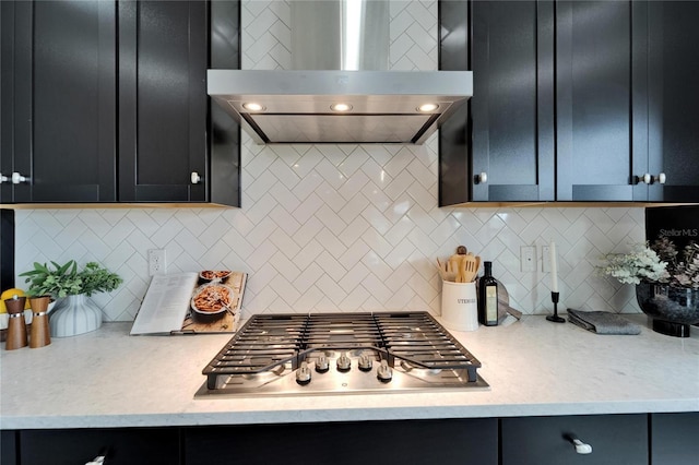 kitchen featuring light countertops, tasteful backsplash, wall chimney exhaust hood, and stainless steel gas stovetop