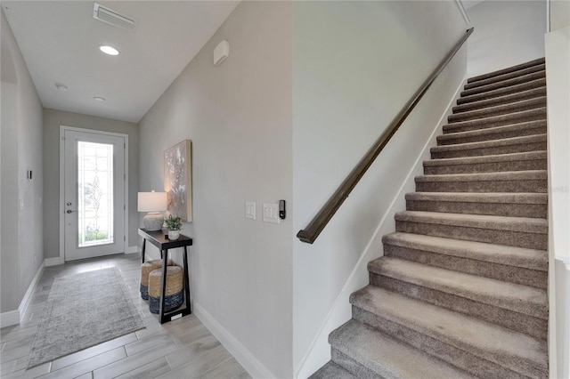 staircase with visible vents, baseboards, recessed lighting, and wood finished floors