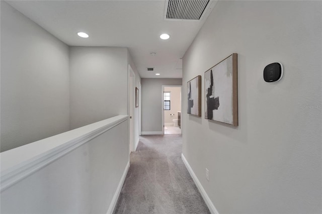 hall featuring light carpet, baseboards, visible vents, and recessed lighting