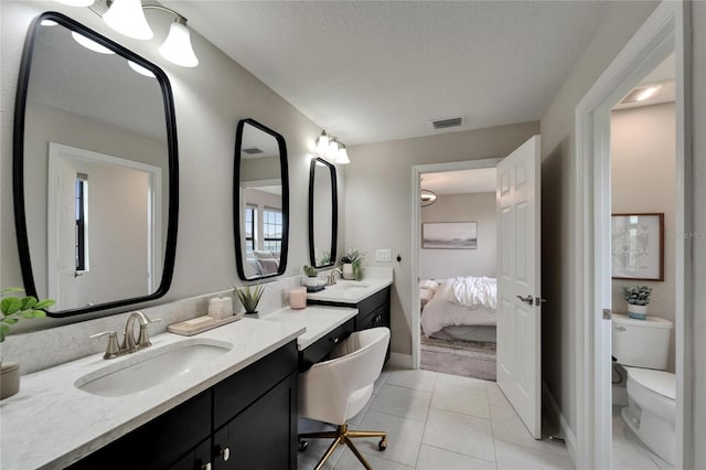 ensuite bathroom with a sink, visible vents, toilet, and double vanity