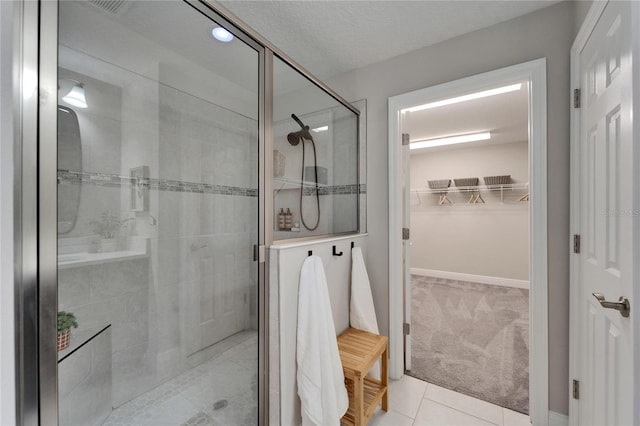 full bathroom featuring a spacious closet, tile patterned floors, and a stall shower