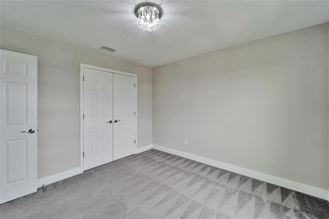 unfurnished bedroom featuring a closet, baseboards, carpet flooring, a textured ceiling, and visible vents