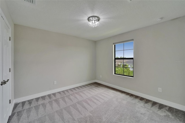 carpeted empty room with baseboards and a textured ceiling