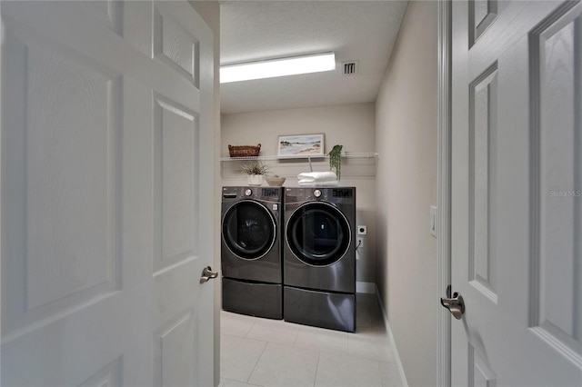 clothes washing area featuring separate washer and dryer, baseboards, light tile patterned floors, visible vents, and laundry area