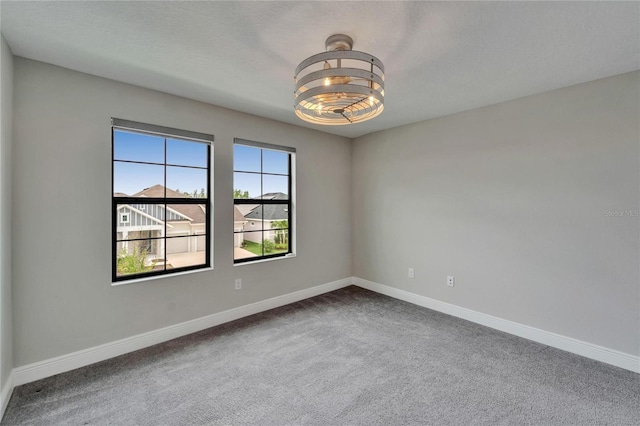 spare room with baseboards and dark colored carpet