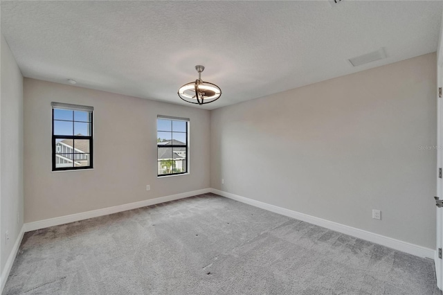carpeted empty room featuring visible vents, baseboards, a notable chandelier, and a textured ceiling