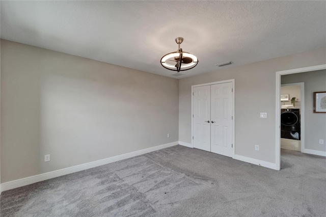 unfurnished bedroom featuring washer / clothes dryer, a closet, baseboards, carpet floors, and visible vents