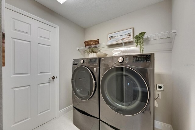 5601 Limelight Dr, Apollo Beach, FL 33572 - laundry area featuring light tile patterned floors, washer and clothes dryer, and a textured ceiling