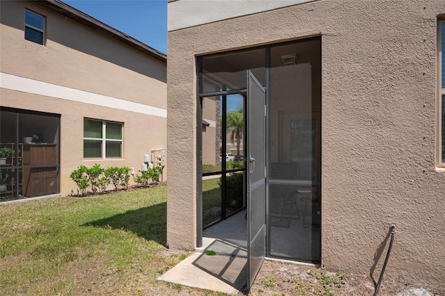 11704 Castine St, New Port Richey, FL 34654 - doorway to property featuring stucco siding and a lawn