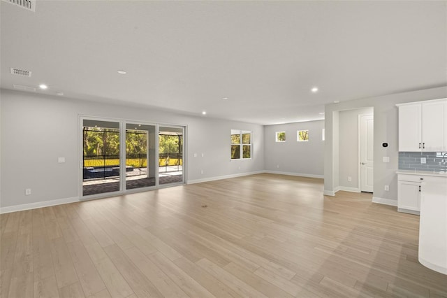 unfurnished living room featuring light wood-style floors, baseboards, recessed lighting, and visible vents