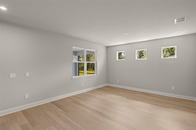 spare room featuring baseboards, visible vents, and light wood-style floors