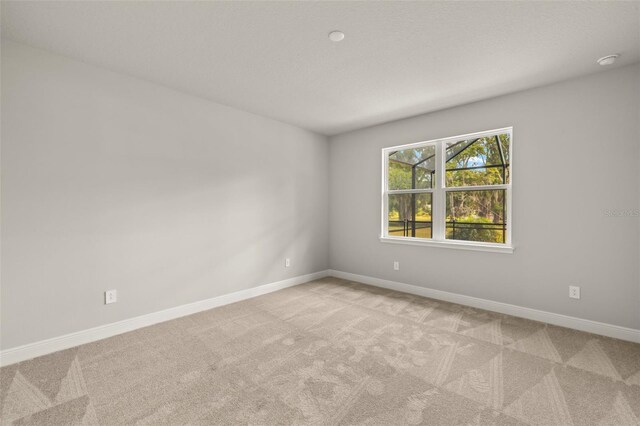 empty room featuring baseboards and light carpet