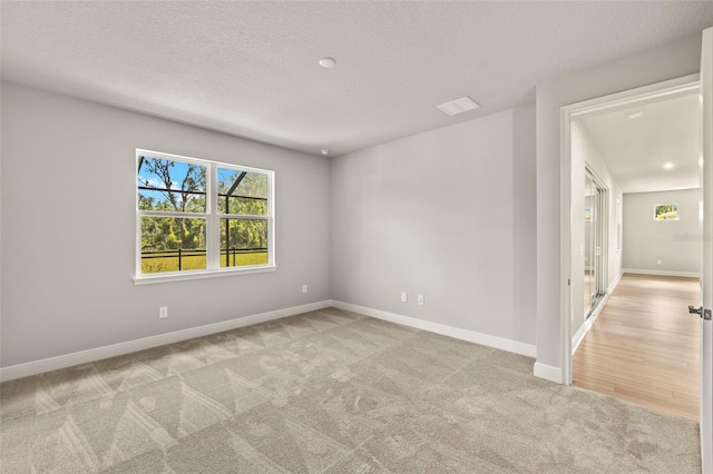 carpeted empty room featuring baseboards and a textured ceiling