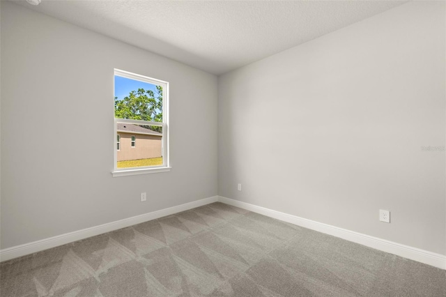 unfurnished room with a textured ceiling, baseboards, and light carpet