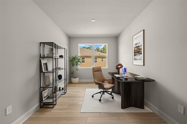 office space with a textured ceiling, baseboards, and light wood finished floors