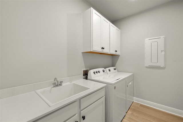 laundry room featuring baseboards, light wood-style floors, separate washer and dryer, a sink, and cabinet space
