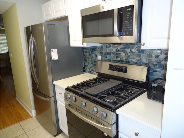 10034 64th Ave N Unit 21, Saint Petersburg, FL 33708 - kitchen with light tile patterned floors, light countertops, white cabinetry, and stainless steel appliances