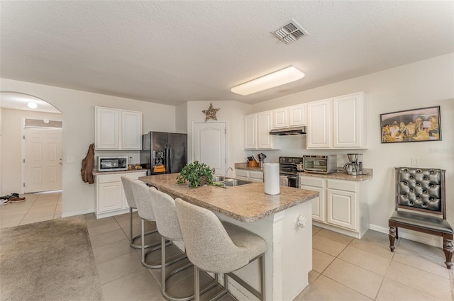 5597 Forest Ridge Dr, Winter Haven, FL 33881 - kitchen featuring appliances with stainless steel finishes, a sink, light tile patterned floors, under cabinet range hood, and white cabinets