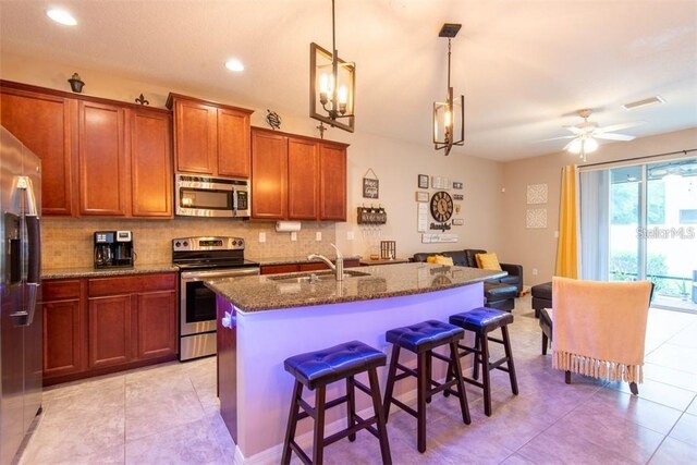 10425 Yellow Spice Ct, Riverview, FL 33578 - kitchen featuring a kitchen bar, dark stone countertops, appliances with stainless steel finishes, a sink, and decorative backsplash