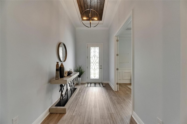foyer featuring an inviting chandelier, baseboards, ornamental molding, and light wood-style flooring