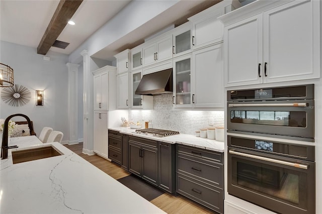 kitchen featuring stainless steel gas cooktop, white cabinetry, a sink, double wall oven, and exhaust hood