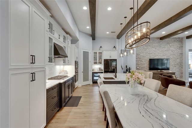kitchen featuring open floor plan, a sink, a breakfast bar, and beamed ceiling