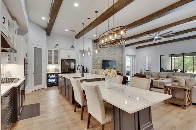 kitchen featuring a breakfast bar, a sink, beam ceiling, open floor plan, and a spacious island