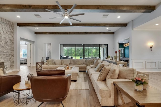 living room with visible vents, light wood-style flooring, ceiling fan, and beamed ceiling