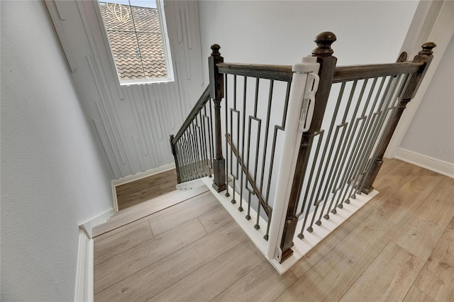 staircase featuring baseboards and wood finished floors