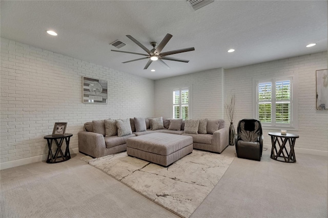 living area featuring carpet flooring, brick wall, and visible vents