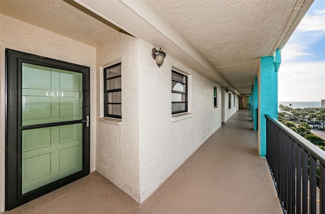 view of exterior entry featuring a balcony and stucco siding